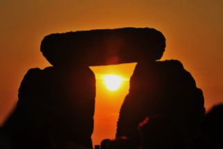 WILTSHIRE, ENGLAND - JUNE 21: Revellers watch sunrise over Stonehenge during celebrations to mark the summer solstice at the prehistoric monument on June 21, 2014 in Wiltshire, England. An estimated 37,000 revellers and modern day druids gathered at Stonehenge, a tradition dating back thousands of years, to celebrate the solstice and watch the sunrise. (Photo by Rufus Cox/Getty Images)